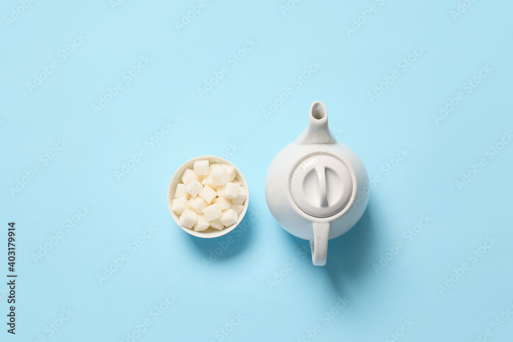 Teapot and sugar bowl on color background