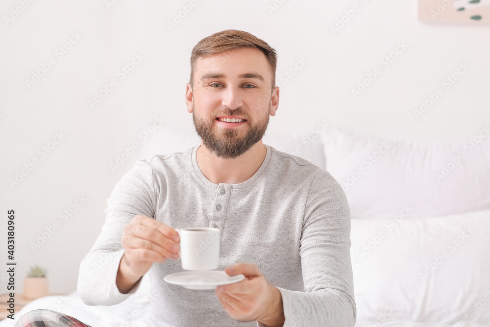 Morning of young man drinking hot coffee in bed