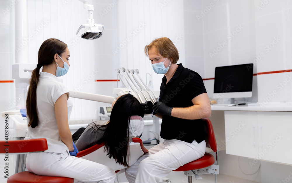 Dentist and assistant treat patient`s teeth with professional instruments. Dentistry concept.