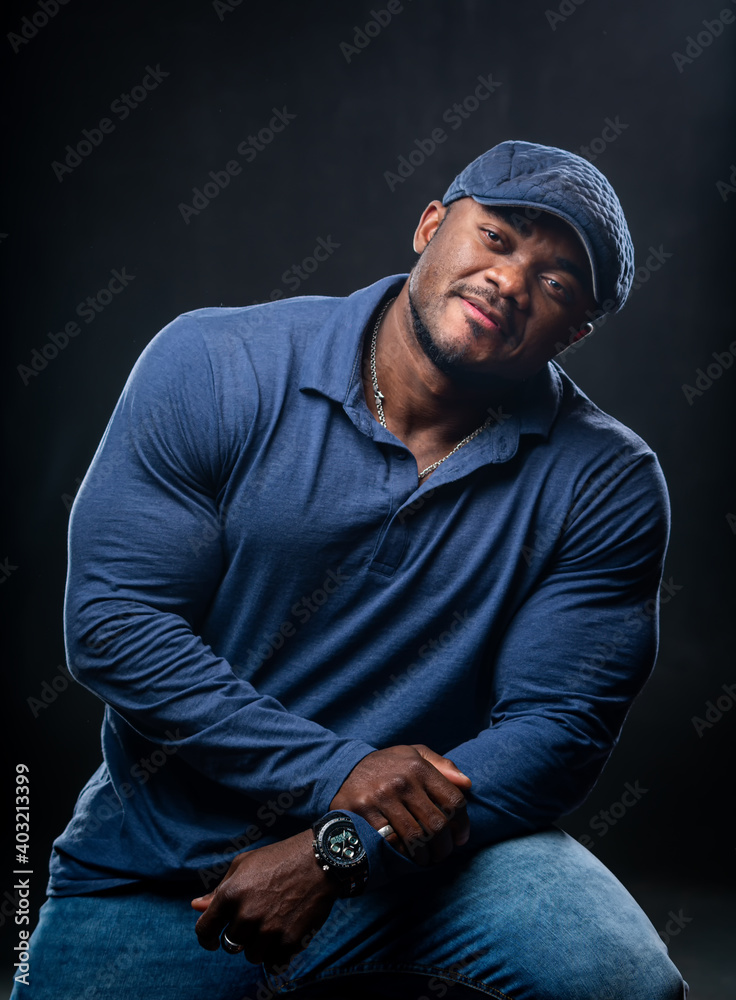 Handsome muscular african american in casual fashion outfit. Blue tones in clothes. Black background