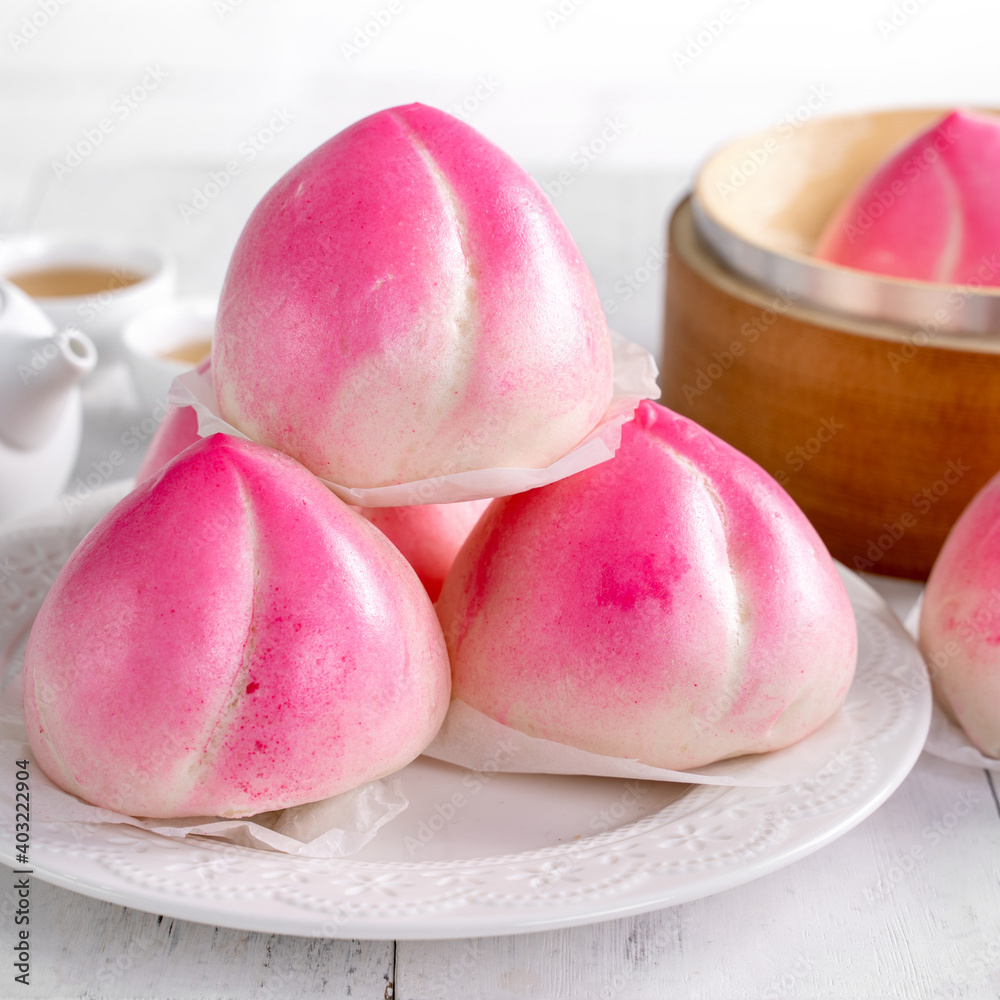 Pink Chinese peach birthday bun food on white table background.