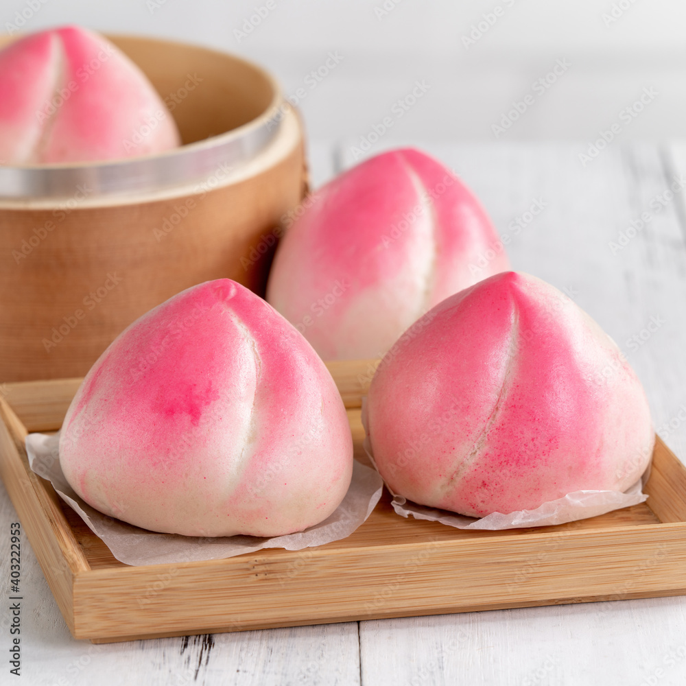 Pink Chinese peach birthday bun food on white table background.