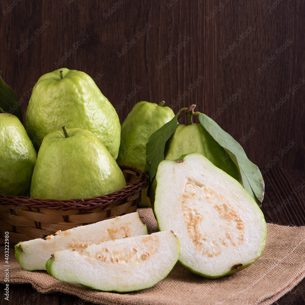 Close up of delicious guava with fresh green leaves on wooden background.