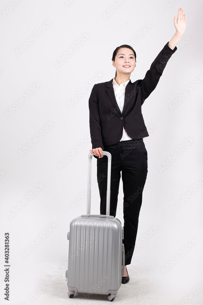 A business lady in a suit pulls a suitcase 