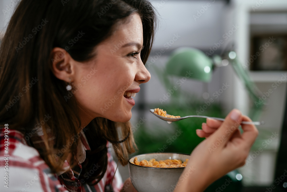 Young businesswoman eating oatmeal in her office. Beautiful woman eating healthy meal while working.