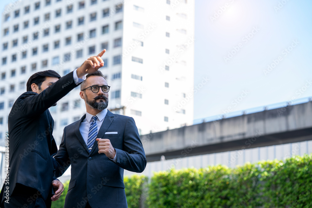 Business people talking to his business partner at outside modern office building.