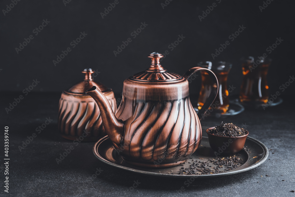 Teapot of tasty Turkish tea and dry leaves on table