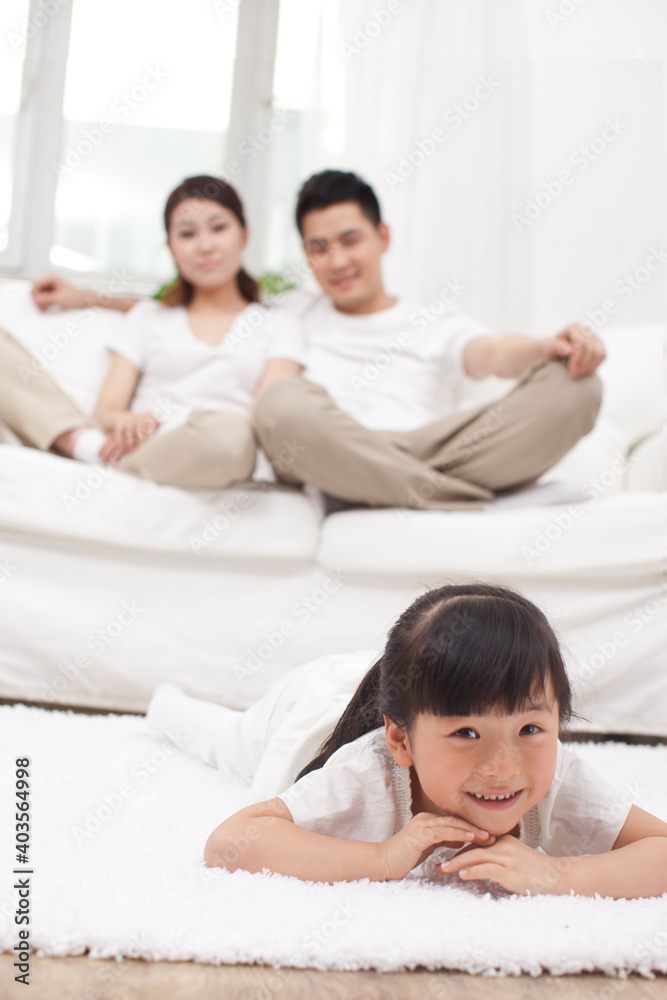 Young Chinese girl in a living room with parents in the background