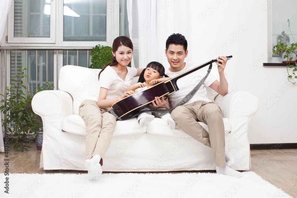 Young family playing guitar in living room