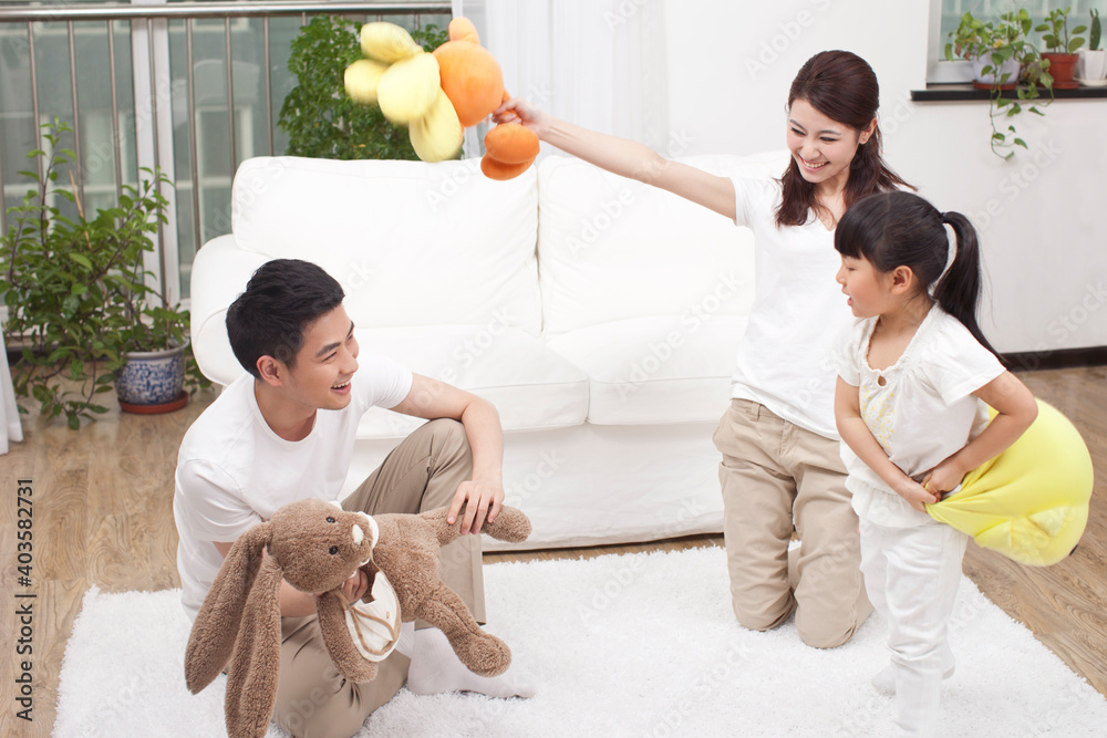 A happy family of three is playing in the living room 