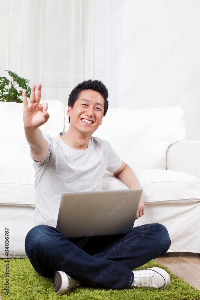 Cheerful businessman using a laptop computer on carpet