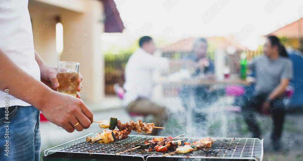 Close up young man grilling a barbecue at a home outdoor party.