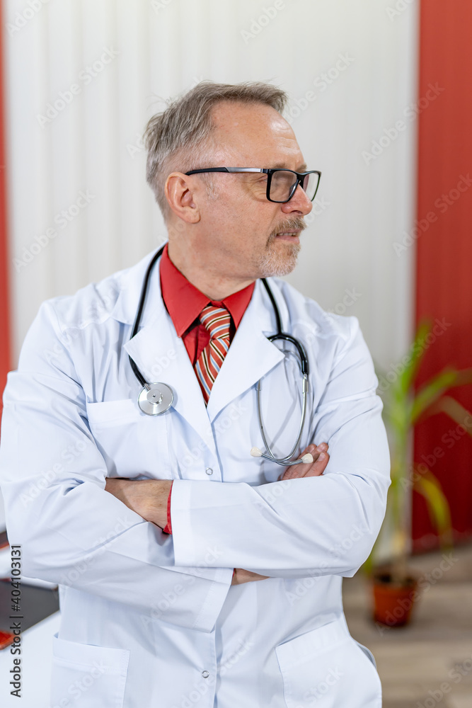 Portrait of a senior male doctor sitting at doctors office and looking at side. Thoughtful face of 