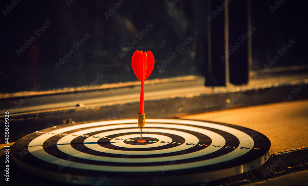 Dart arrow hit on bulleyes of dartboard to represent that the business reached the target  with dark