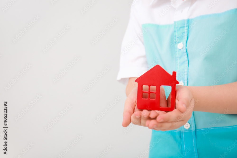 Childs hands with figure of house on light background