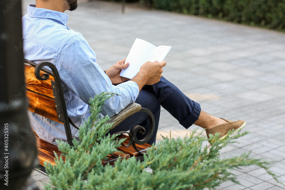 Young man with blank magazine in park