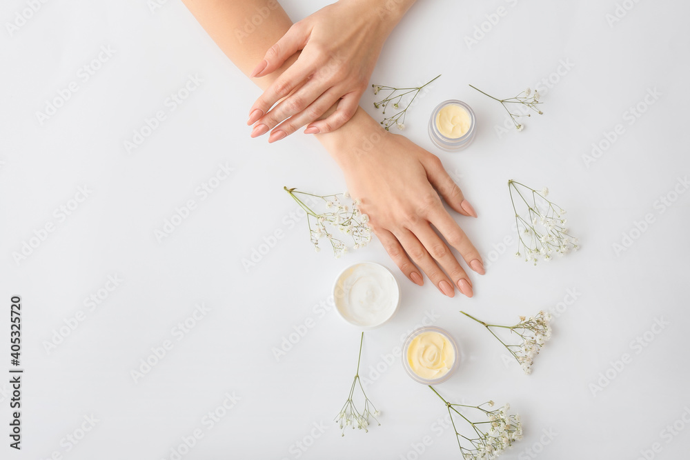 浅背景上有奶油和美丽花朵的女性手