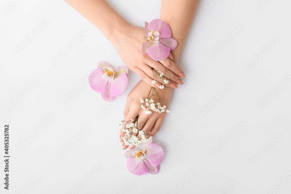 Female hands with beautiful flowers on light background