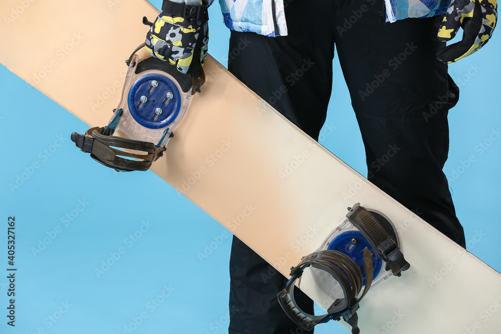 Male snowboarder on color background