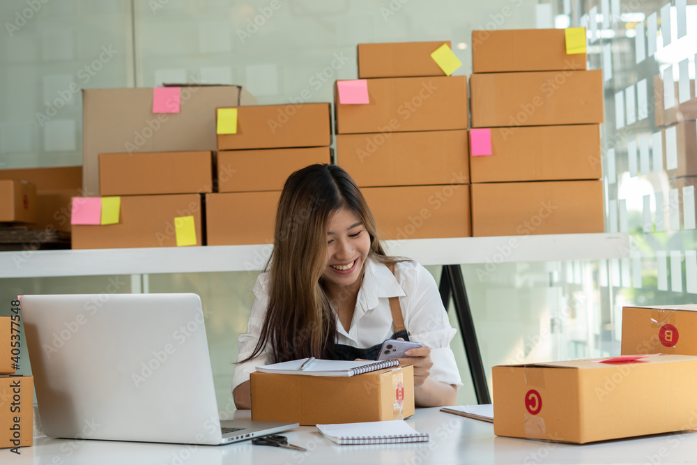 An Asian owner holds a package in a brown box, ready for delivery to a customer who orders online. A