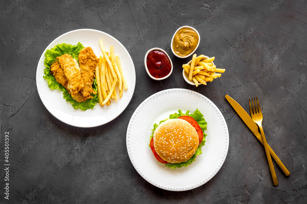 Burger with fried potatoes and chicken, top view