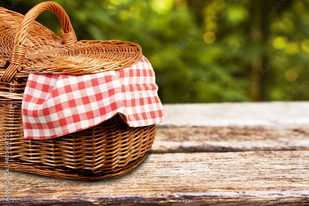 Picnic basket with a tablecloth on a wooden table