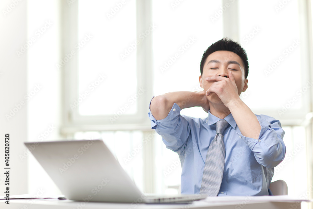 Portrait of young businessman Yawning in office