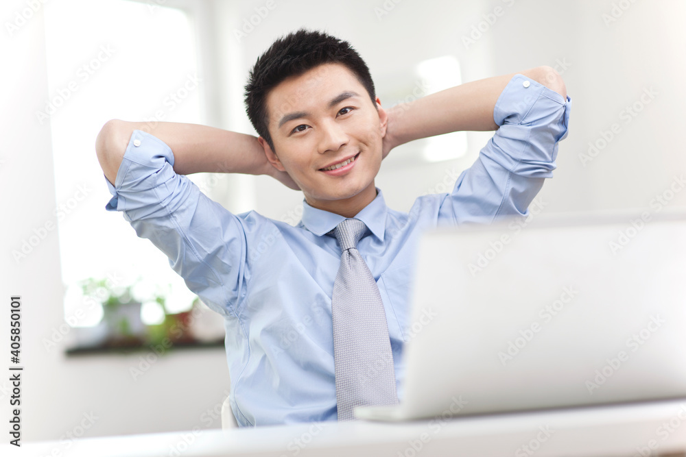 Portrait of young businessman relaxing in front of laptop