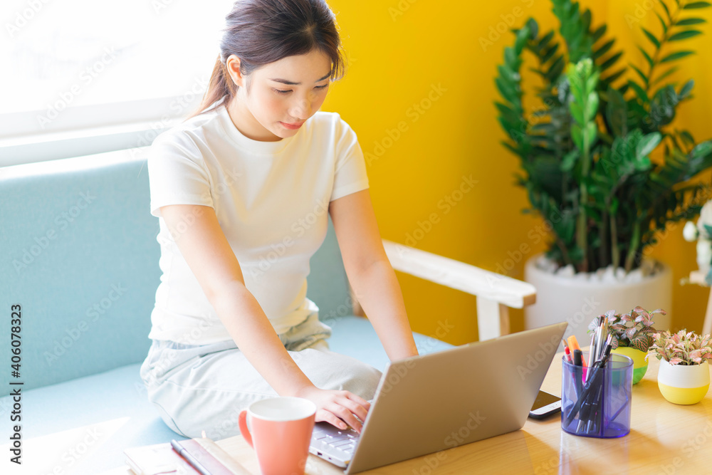 Young asian woman sitting on sofa working at home