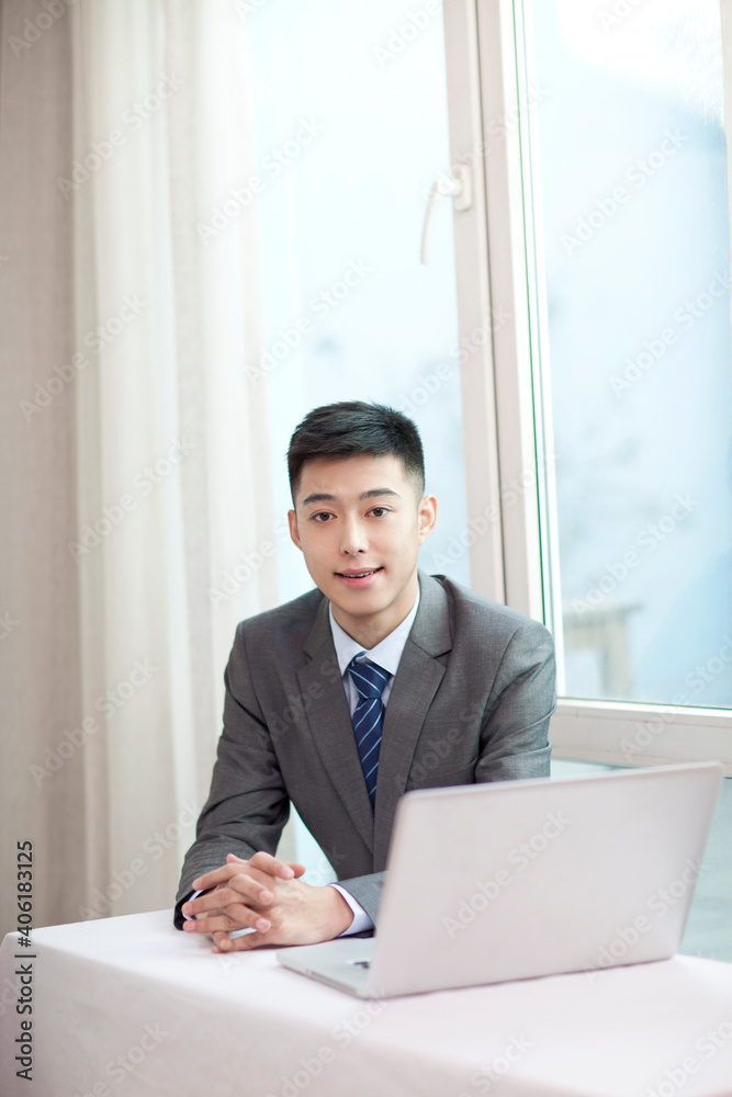 Portrait of young bisinessman sitting in the front of laptop 