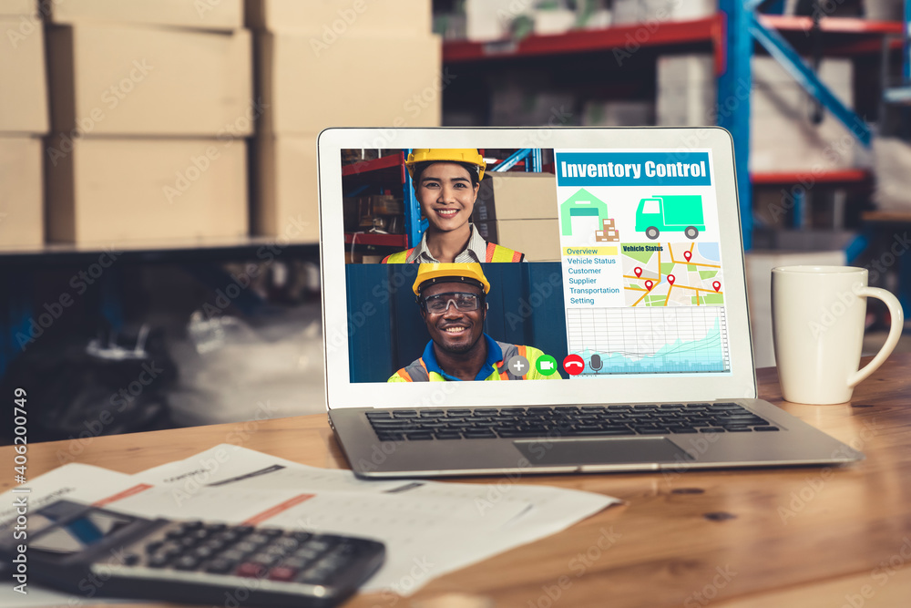 Warehouse staff talking on video call at computer screen in storage warehouse . Online software tech