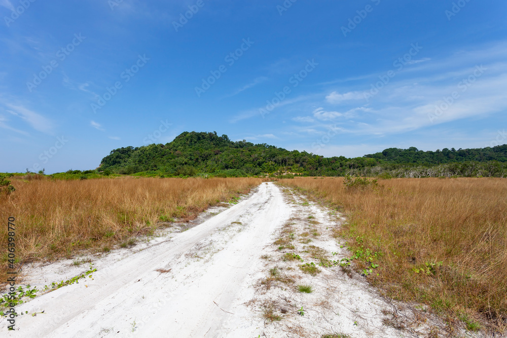 海边的空沙路，穿过干燥的田野，乡村的草地，背靠蓝天的山脉