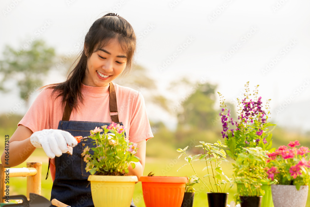 微笑的亚洲年轻女子戴着手套在户外花园种花的肖像