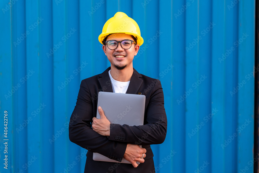 Portrait of Asian Business man import and export goods wear a helmet logitics shipping at container 