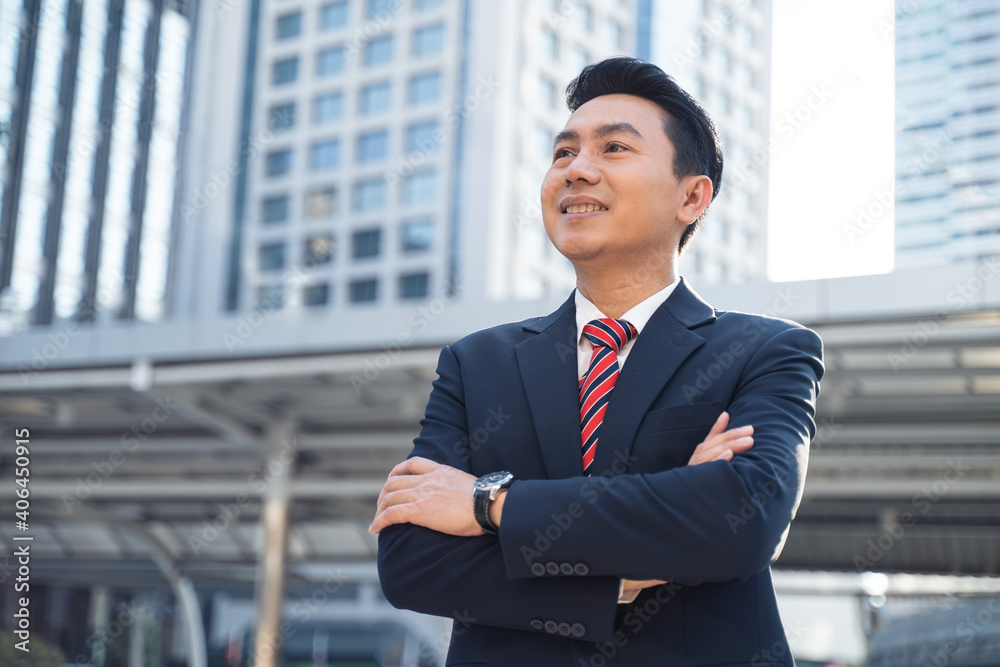 Asian businessman crossing arms, standing outdoor in the city.