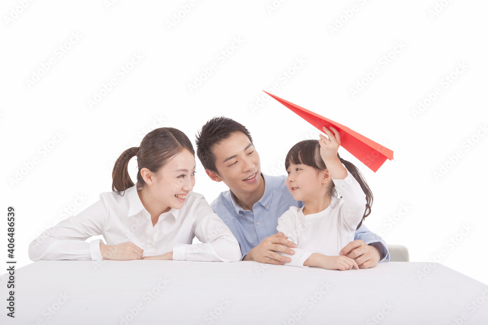 Portrait of daughter playing paper plane with parents