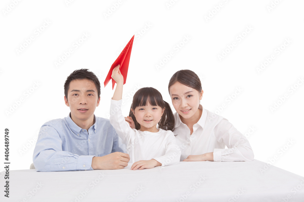 Portrait of daughter holding paper plane,parents sitting on carpet