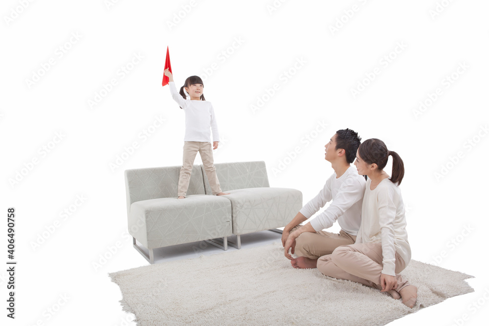 Portrait of daughter playing paper plane,parents sitting on carpet