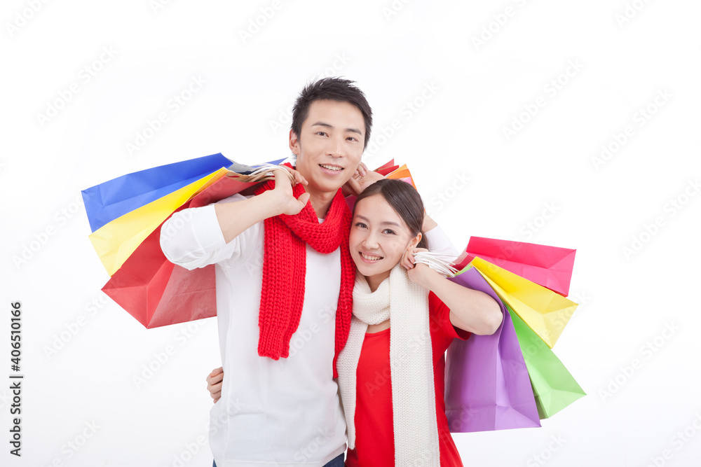 Portrait of young couple holding shopping bags over shoulders