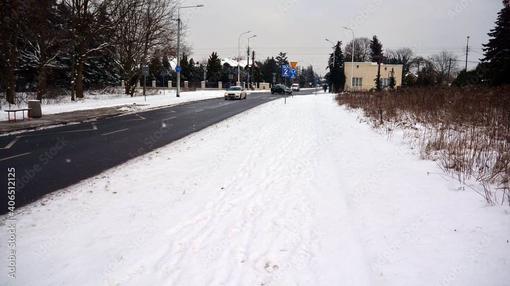 Residential neighborhood in the suburbs during a white snow storm and roads covered in snow. 