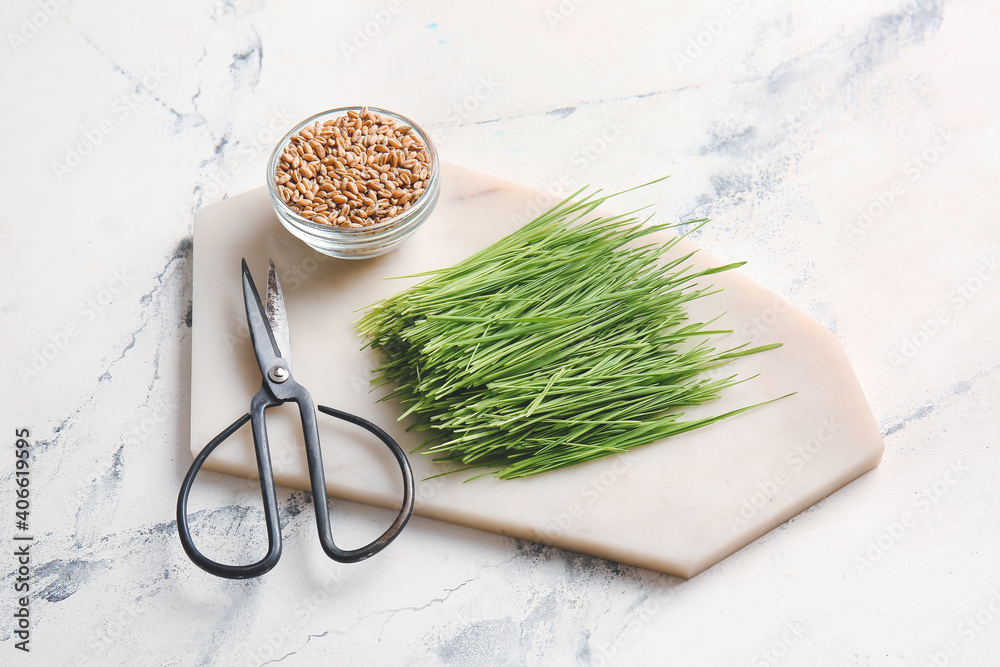 Fresh wheatgrass, seeds in bowl and scissors on light background