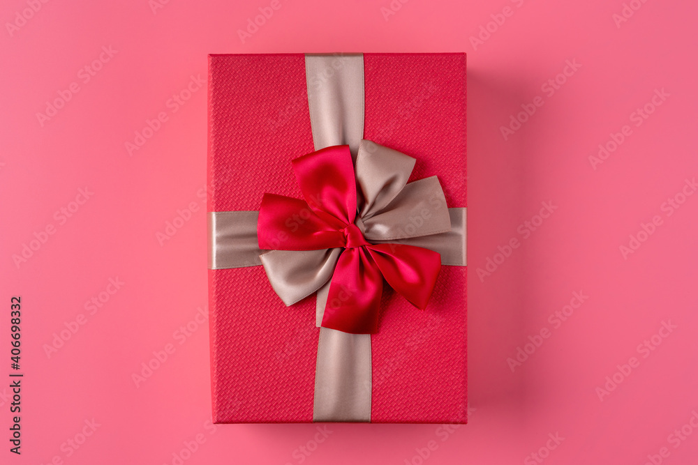 Beautiful gift box with ribbon bow on pink background.