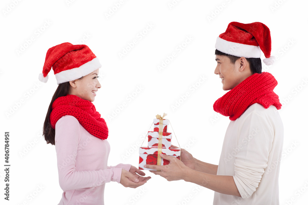 Portrait of young couple wearing Santa hats,holding gift