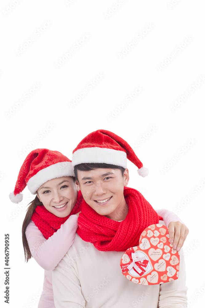 Portrait of young couple wearing Santa hats,holding gift