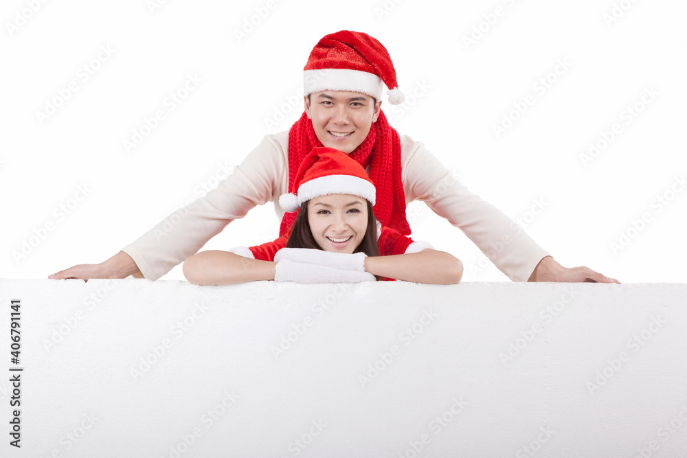 Portrait of young couple wearing santa costumes,and a huge whiteboard