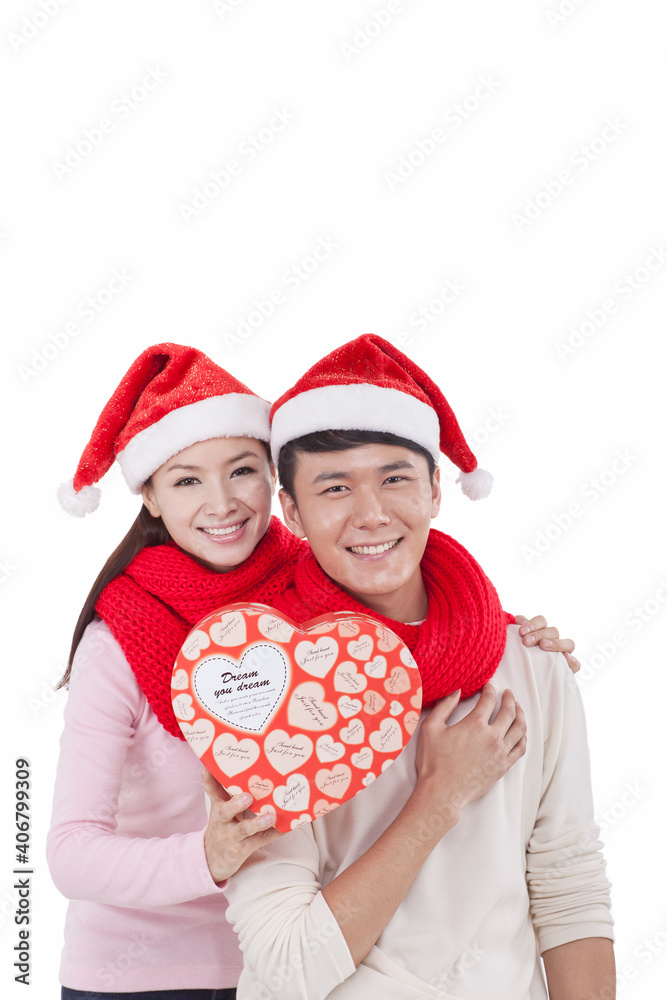 Portrait of young couple wearing Santa hats,holding gift