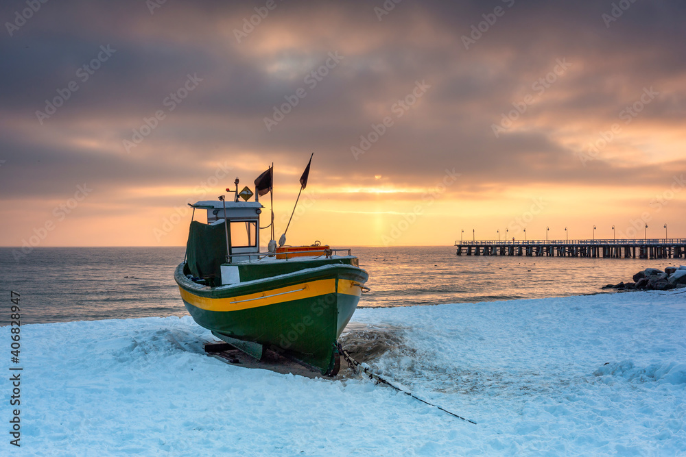 日出时，波兰波罗的海Gdynia Orlowo雪地海滩上的渔船