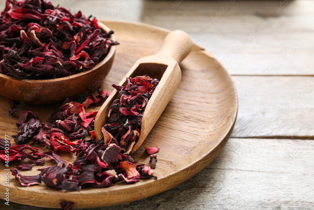 Bowl with dry hibiscus tea on wooden background