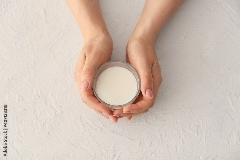 Female hands with glass of rice milk on white background