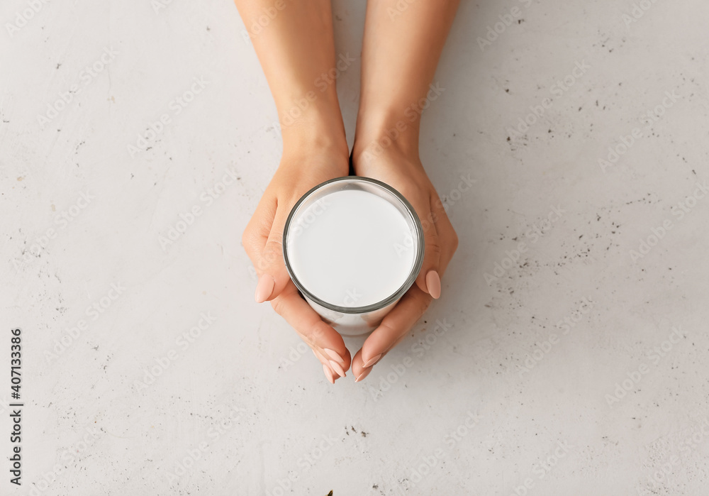 Female hands with glass of rice milk on white background